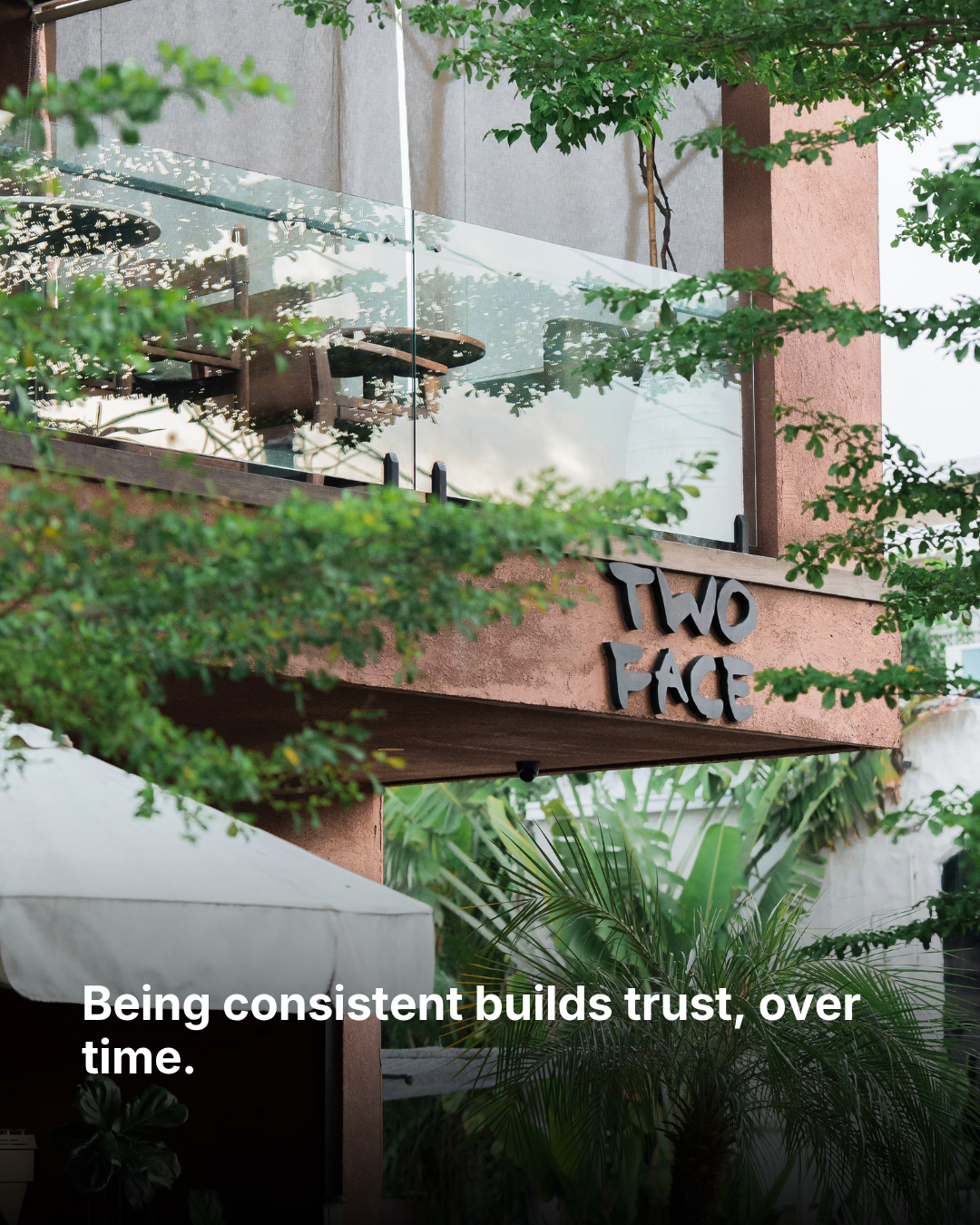 TWO FACE's sign among trees and greenery, with the words “Being consistent builds trust, over time.”