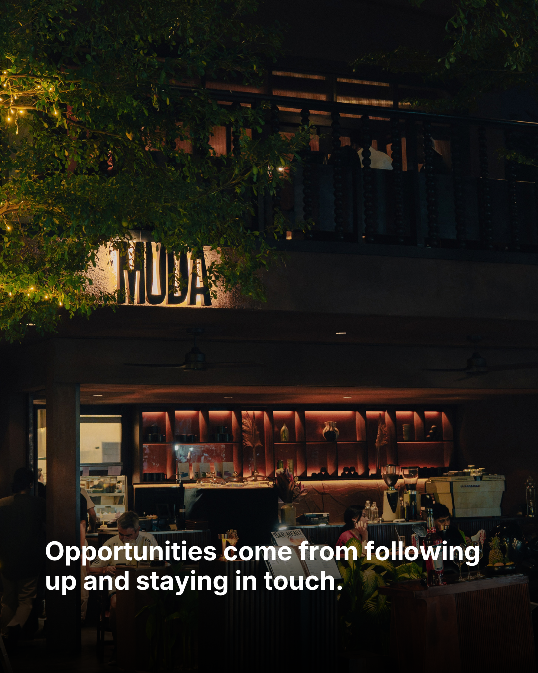 MUDA's entrance at night, with the words “Opportunities come from following up and staying in touch.”