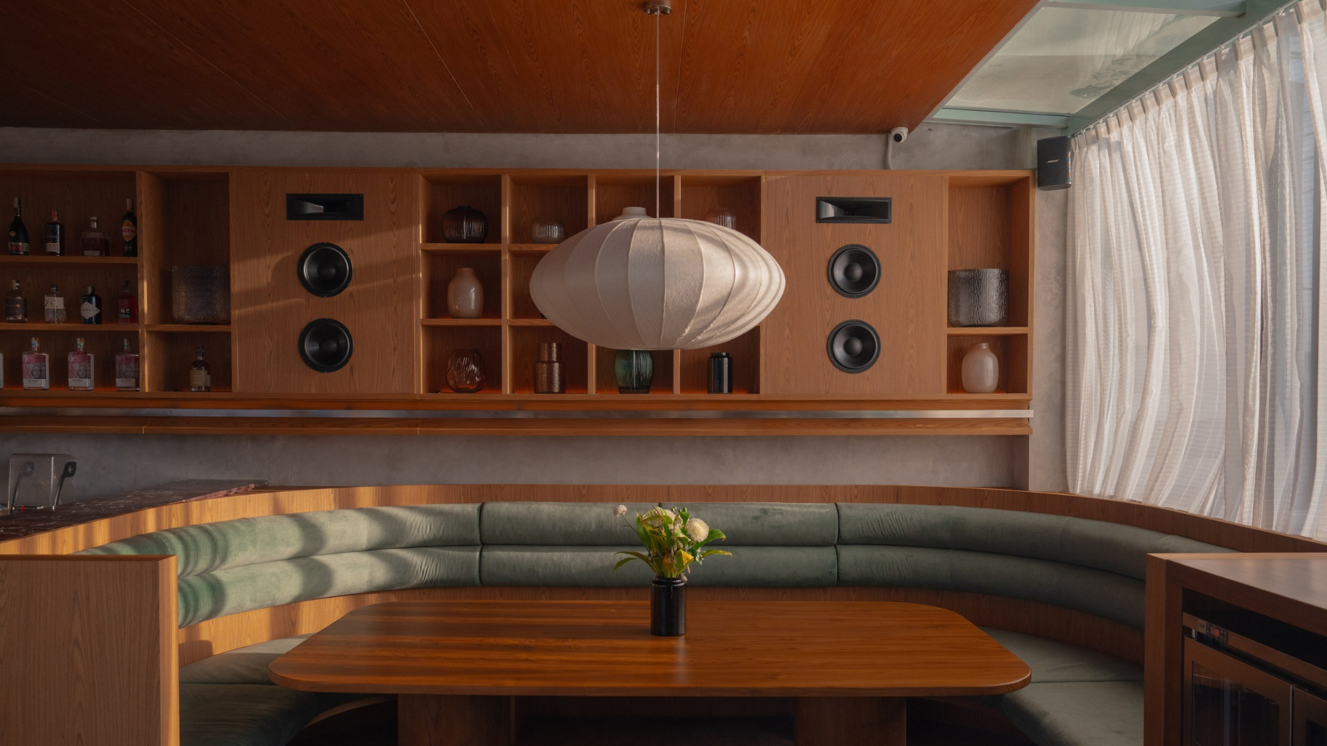 The lounge at LUSA Bistro, with booth seating, wooden shelves and a paper pendant lamp in warm light
